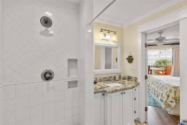 bathroom with vanity, ceiling fan, ornamental molding, and tiled shower