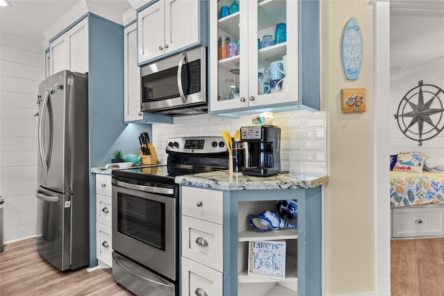 kitchen featuring appliances with stainless steel finishes, white cabinetry, light stone counters, crown molding, and light wood-type flooring