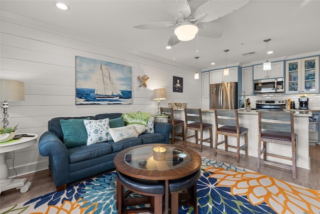 living room with crown molding, ceiling fan, and dark hardwood / wood-style floors