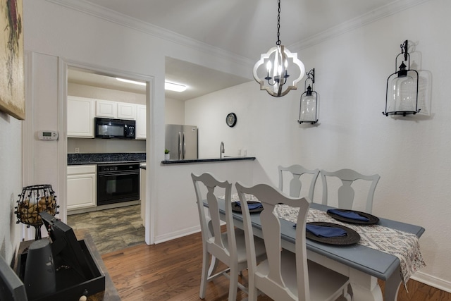 dining room featuring an inviting chandelier, sink, dark wood-type flooring, and ornamental molding