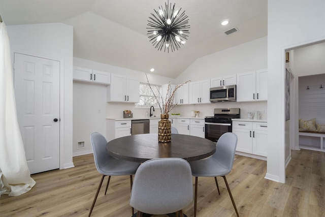 dining room with lofted ceiling, a notable chandelier, light hardwood / wood-style floors, and sink