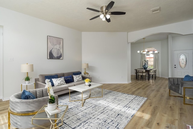 living room with hardwood / wood-style flooring, ceiling fan with notable chandelier, and a textured ceiling