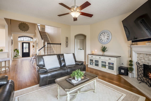 19106 High Canyon Ln, Tomball, TX 77377 - living room with hardwood / wood-style floors, a ceiling fan, a stone fireplace, stairs, and arched walkways