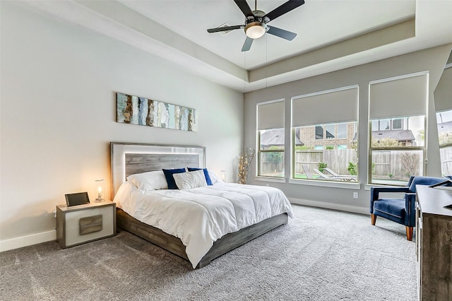 carpeted bedroom featuring a raised ceiling and ceiling fan