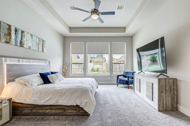 carpeted bedroom featuring ceiling fan and a raised ceiling