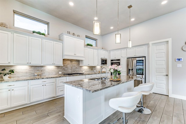 kitchen featuring an island with sink, appliances with stainless steel finishes, sink, and white cabinets