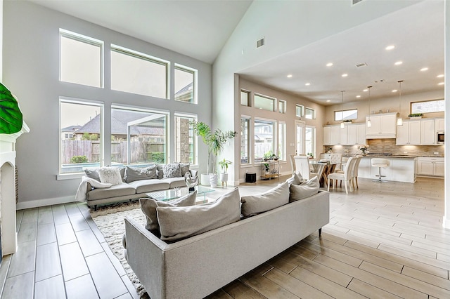 living room with light hardwood / wood-style floors, high vaulted ceiling, and a wealth of natural light