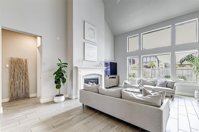 living room featuring a towering ceiling, a high end fireplace, and light hardwood / wood-style floors