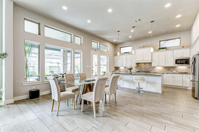 dining area with a towering ceiling and light hardwood / wood-style floors