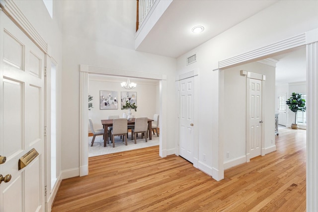 hall with a towering ceiling and light hardwood / wood-style flooring