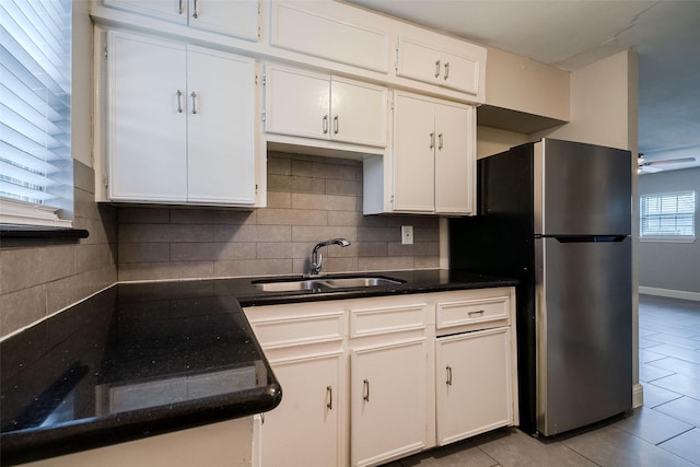 kitchen featuring tasteful backsplash, stainless steel fridge, sink, and white cabinets