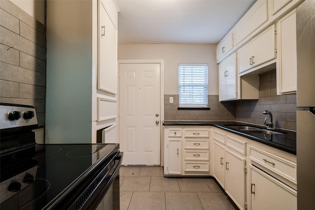 kitchen featuring white cabinetry, light tile patterned floors, sink, and electric range