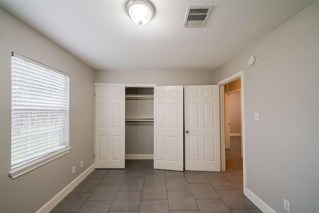 unfurnished bedroom featuring a closet and dark tile patterned floors