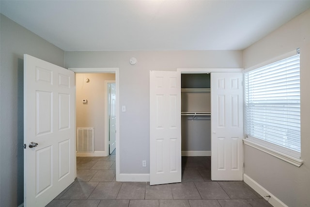 unfurnished bedroom with tile patterned flooring and a closet