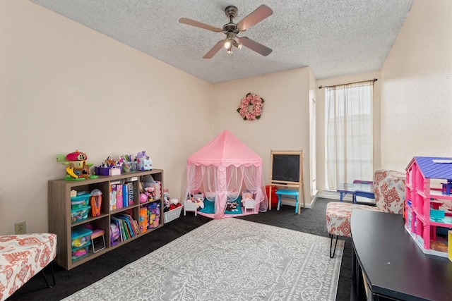 playroom with ceiling fan, dark carpet, and a textured ceiling