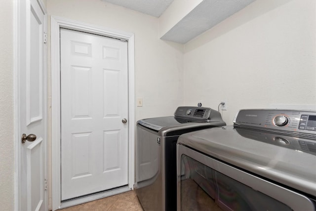 laundry area with washing machine and dryer and light tile patterned floors