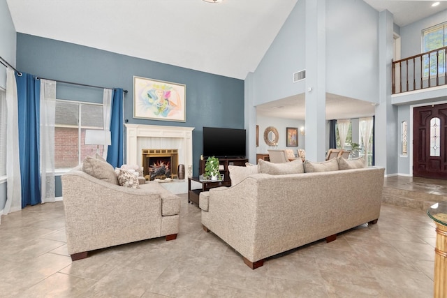 living room featuring a tiled fireplace, a wealth of natural light, high vaulted ceiling, and light tile patterned flooring