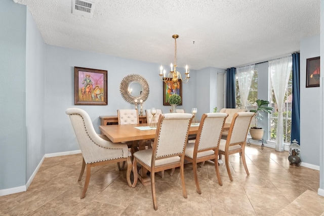 tiled dining space featuring an inviting chandelier and a textured ceiling