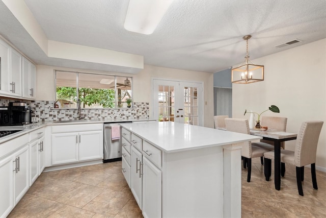 kitchen featuring sink, dishwasher, a center island, decorative light fixtures, and french doors