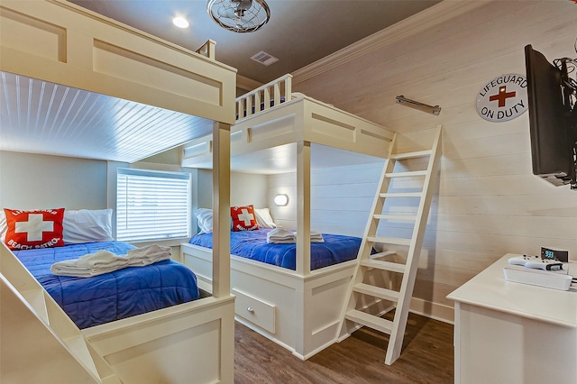 bedroom with hardwood / wood-style flooring and wooden walls