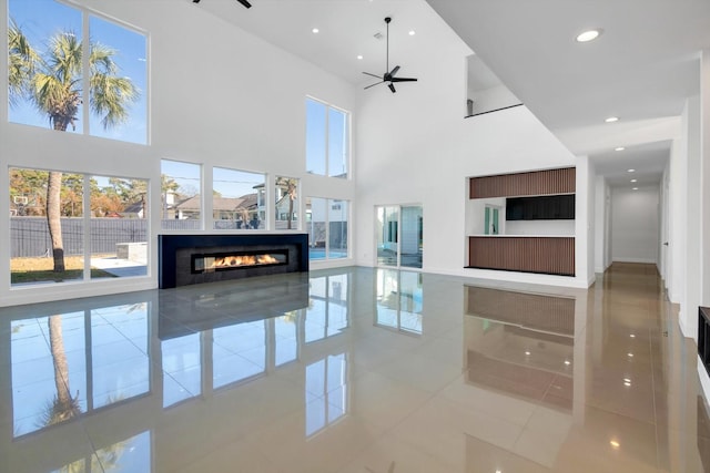 tiled living room featuring ceiling fan and a high ceiling