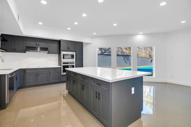 kitchen with sink, gray cabinetry, appliances with stainless steel finishes, a kitchen island, and backsplash