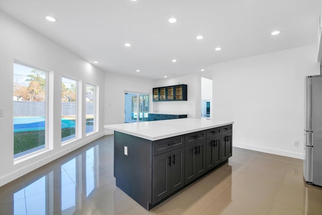 kitchen featuring light tile patterned floors, stainless steel refrigerator, and a kitchen island