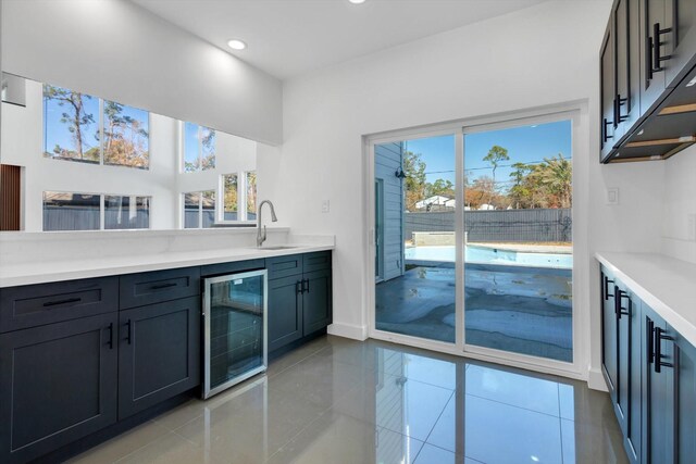 bar with light tile patterned flooring, plenty of natural light, sink, and wine cooler