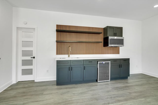 kitchen with gray cabinetry, beverage cooler, sink, and light wood-type flooring