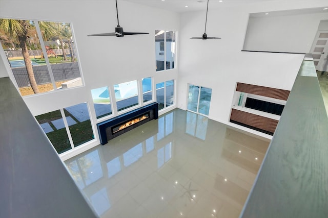 living room with ceiling fan, a towering ceiling, and tile patterned floors