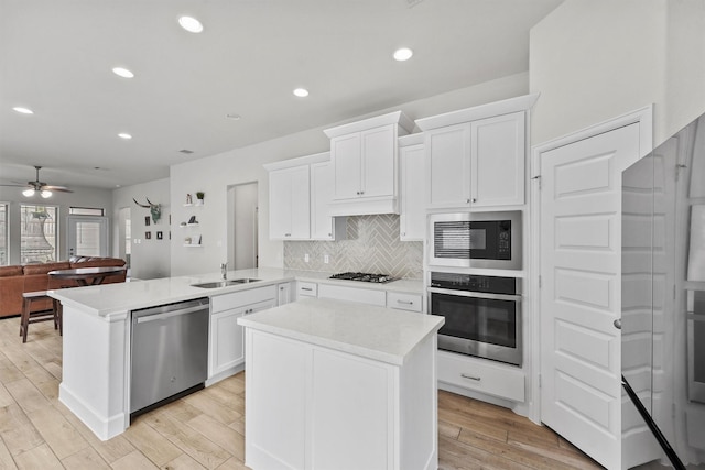 kitchen with stainless steel appliances, white cabinetry, sink, and kitchen peninsula