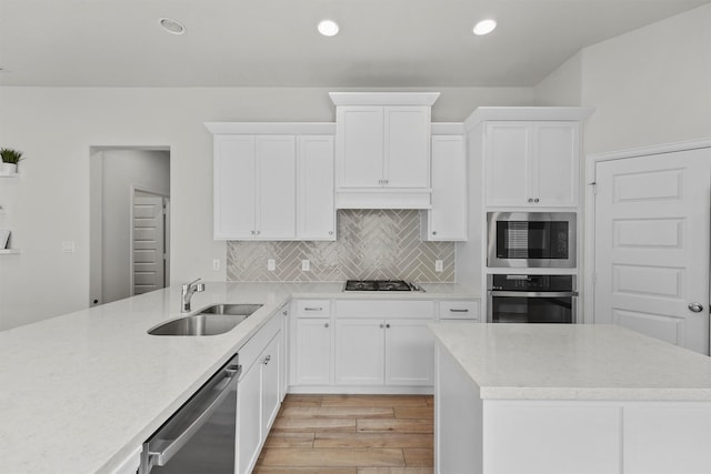 kitchen with stainless steel appliances, white cabinetry, sink, and tasteful backsplash