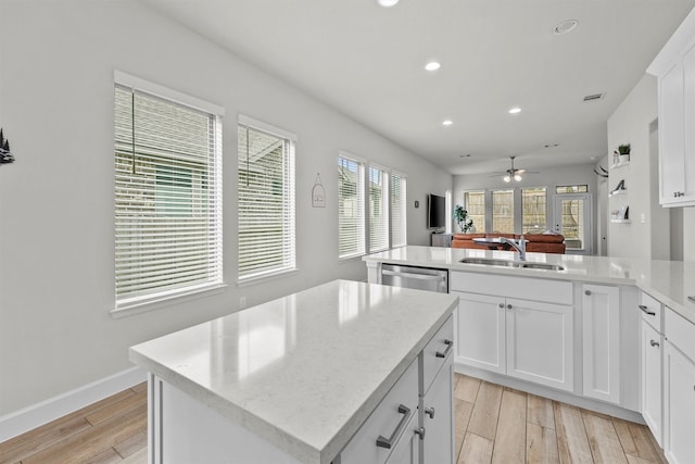 kitchen featuring dishwasher, sink, white cabinets, a center island with sink, and light wood-type flooring