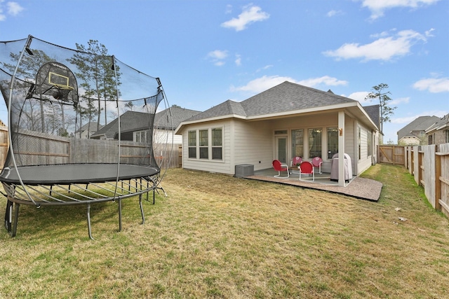 rear view of property featuring cooling unit, a patio area, a trampoline, and a lawn