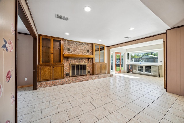 unfurnished living room with a fireplace, built in features, and light tile patterned floors