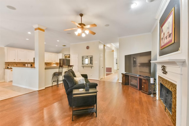 living room with ornate columns, vaulted ceiling, ornamental molding, ceiling fan, and light hardwood / wood-style floors