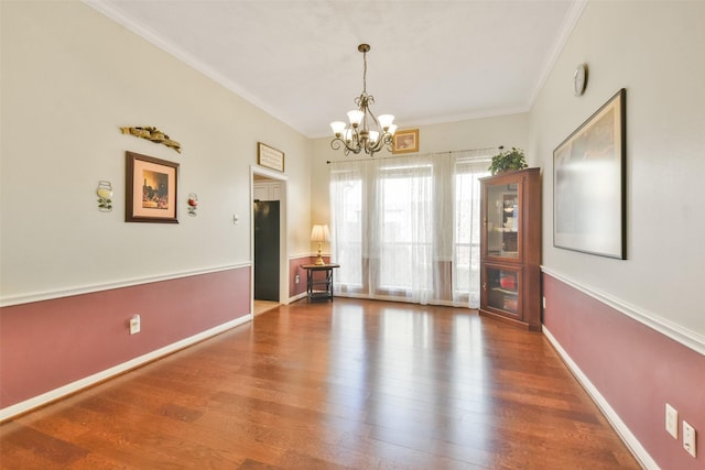 unfurnished dining area featuring an inviting chandelier, hardwood / wood-style flooring, and ornamental molding