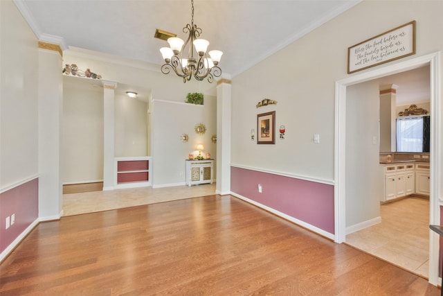 empty room with crown molding, a notable chandelier, and light wood-type flooring