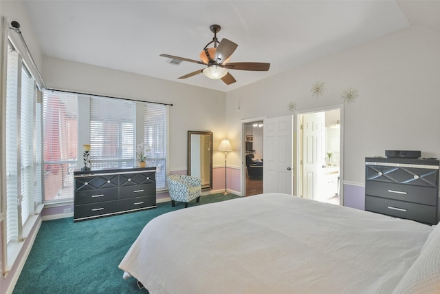 bedroom with ceiling fan, lofted ceiling, connected bathroom, and dark carpet