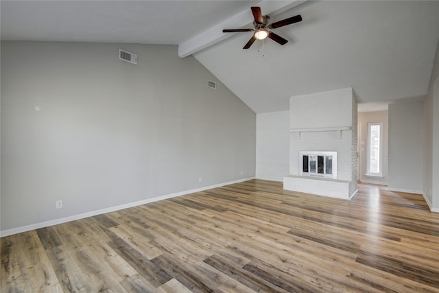 unfurnished living room featuring ceiling fan, a fireplace, lofted ceiling with beams, and light wood-type flooring