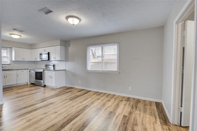 kitchen featuring stainless steel appliances, tasteful backsplash, white cabinets, and light hardwood / wood-style flooring