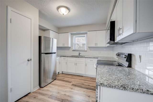 kitchen featuring sink, white cabinets, light hardwood / wood-style floors, stainless steel appliances, and light stone countertops