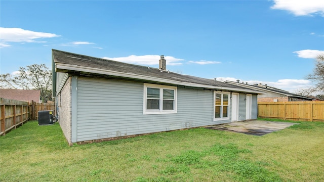 rear view of house with cooling unit and a lawn