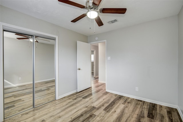 unfurnished bedroom with ceiling fan, a closet, and light wood-type flooring