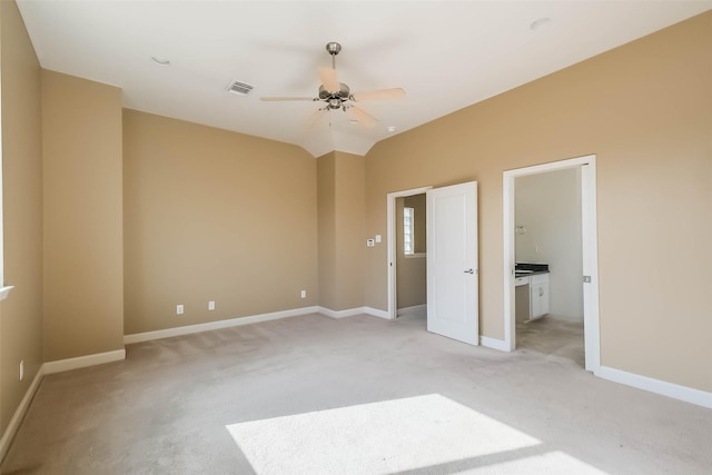 unfurnished bedroom with light carpet, ensuite bath, vaulted ceiling, and ceiling fan