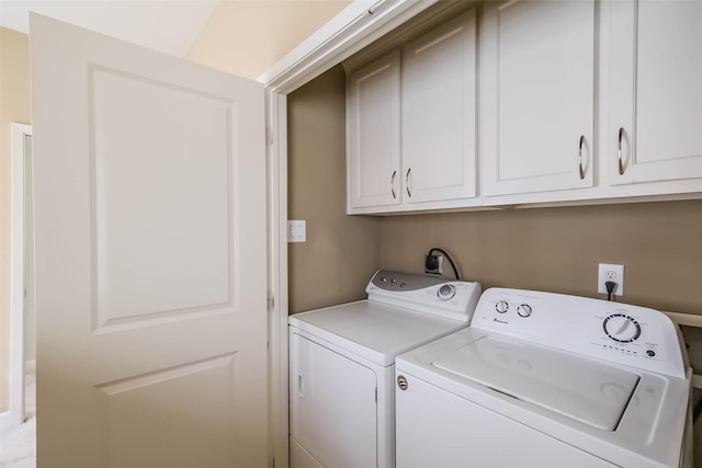 clothes washing area featuring washing machine and dryer and cabinets