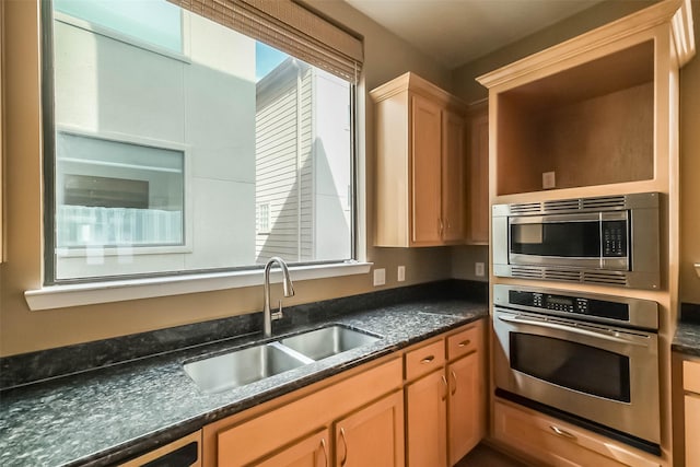 kitchen with appliances with stainless steel finishes, sink, dark stone countertops, and light brown cabinets