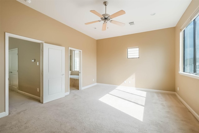 unfurnished bedroom featuring ceiling fan, ensuite bath, light carpet, and multiple windows