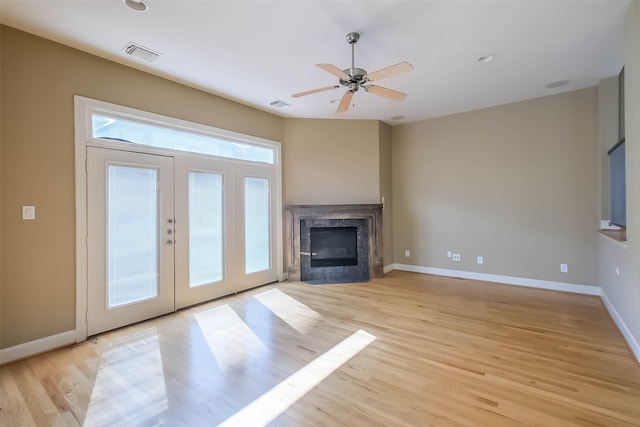 unfurnished living room featuring ceiling fan, a high end fireplace, and light hardwood / wood-style flooring