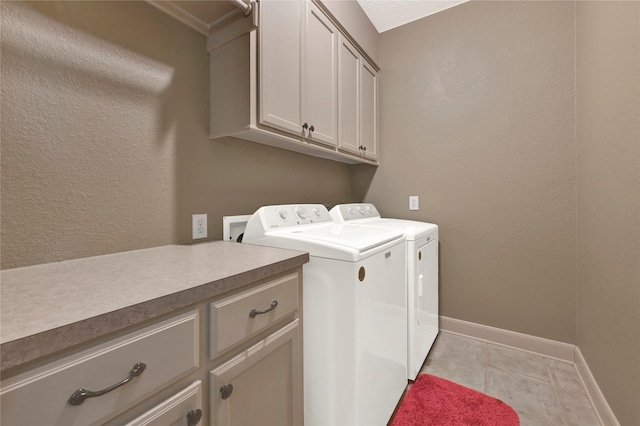 washroom with light tile patterned flooring, cabinets, and washer and clothes dryer